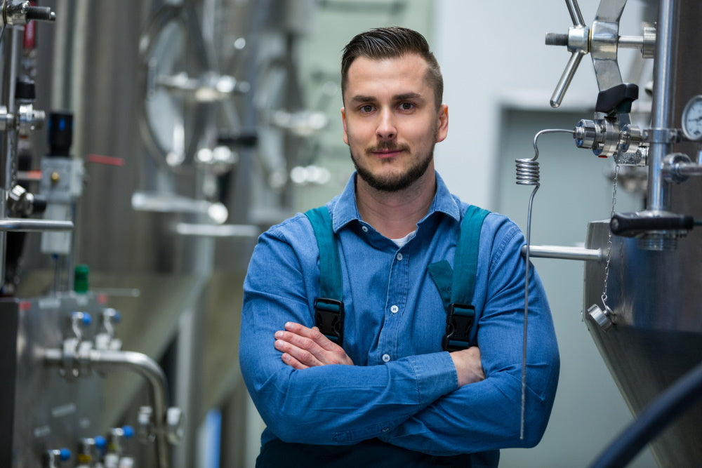 a man standing with his arms crossed in front of various industrial machines.