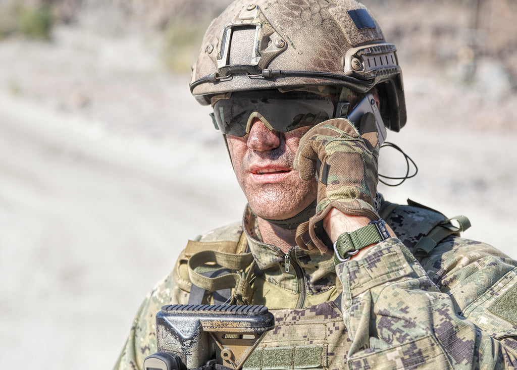 a solider is on the phone and has various hook and loop tapes attached to his uniform.