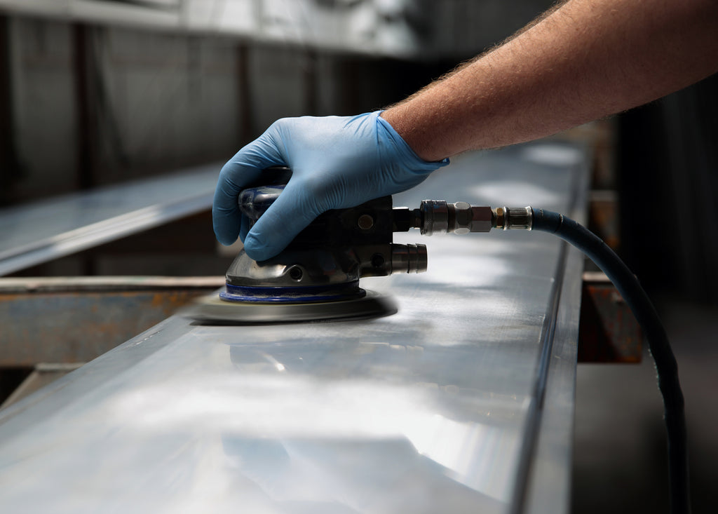 someone is using a handheld machine to buff metal sheets. Hook and loop is used in the machine